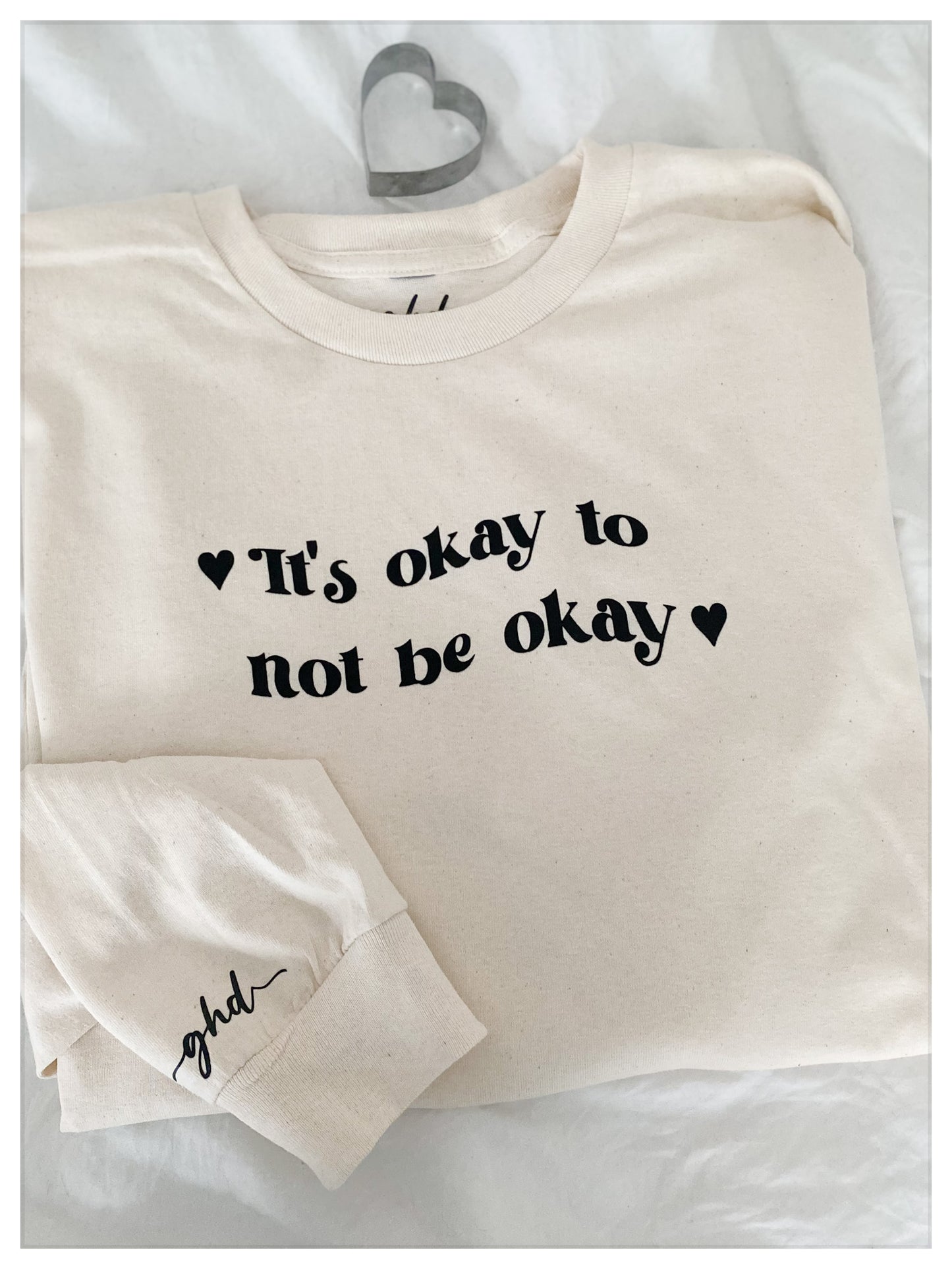 "It's Ok To Not Be Ok " Tee folded up with A heart cookie cutter on top