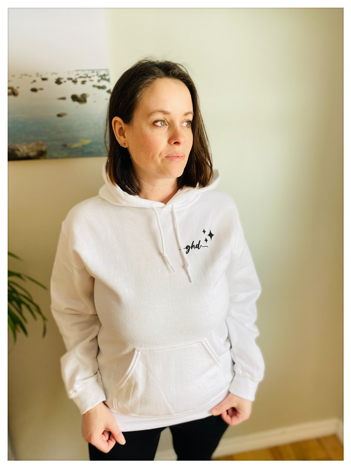 Front view of the white fleeced hoodie, that has the "ghd" logo written on the upper front left side with three stars in different sizes beside it. 